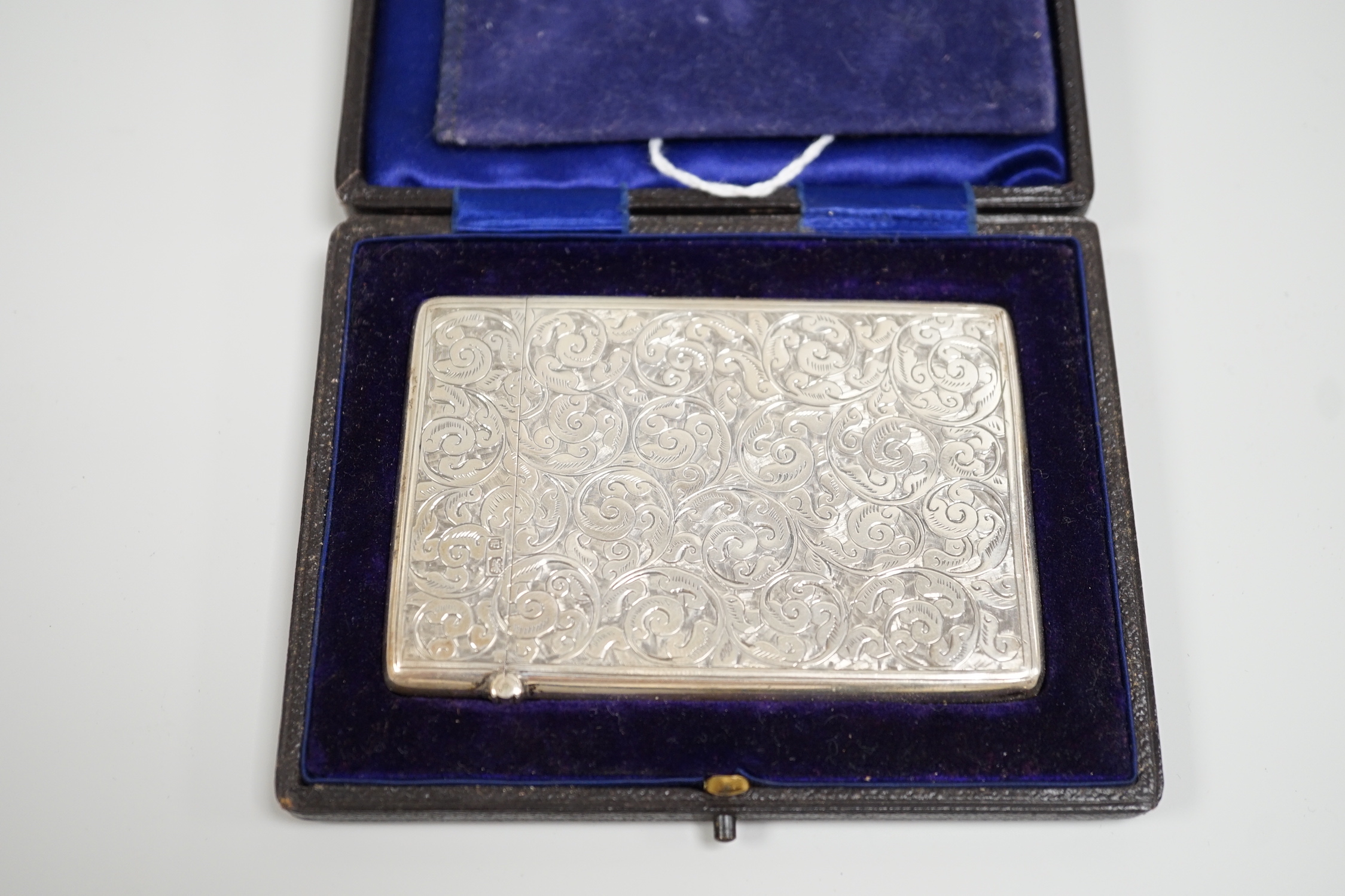 An Edwardian chased silver rectangular card case, Deakin & Francis, Birmingham, 1903, 95mm, in fitted leather case.